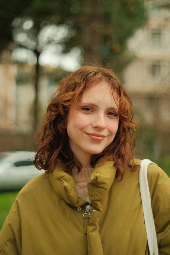 A woman with red hair is standing in the grass