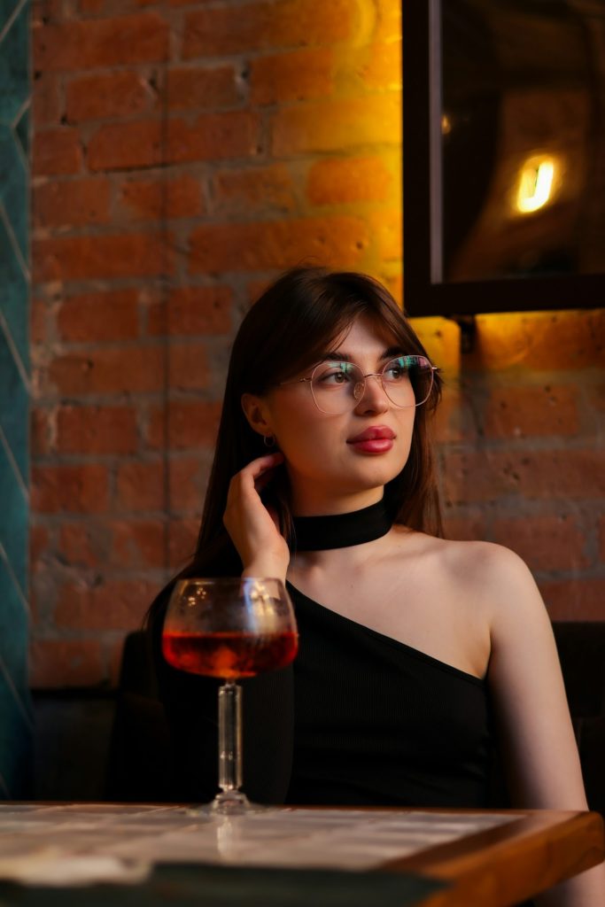 a woman sitting at a table with a glass of wine
