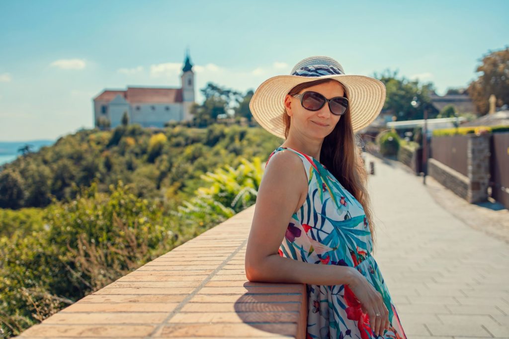 hungarian woman in blue and white floral halter top sitting on brown wooden dock during daytime