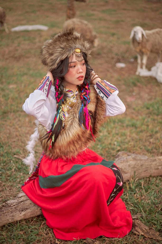 kyrgyzstan woman sitting on a log wearing a fur hat