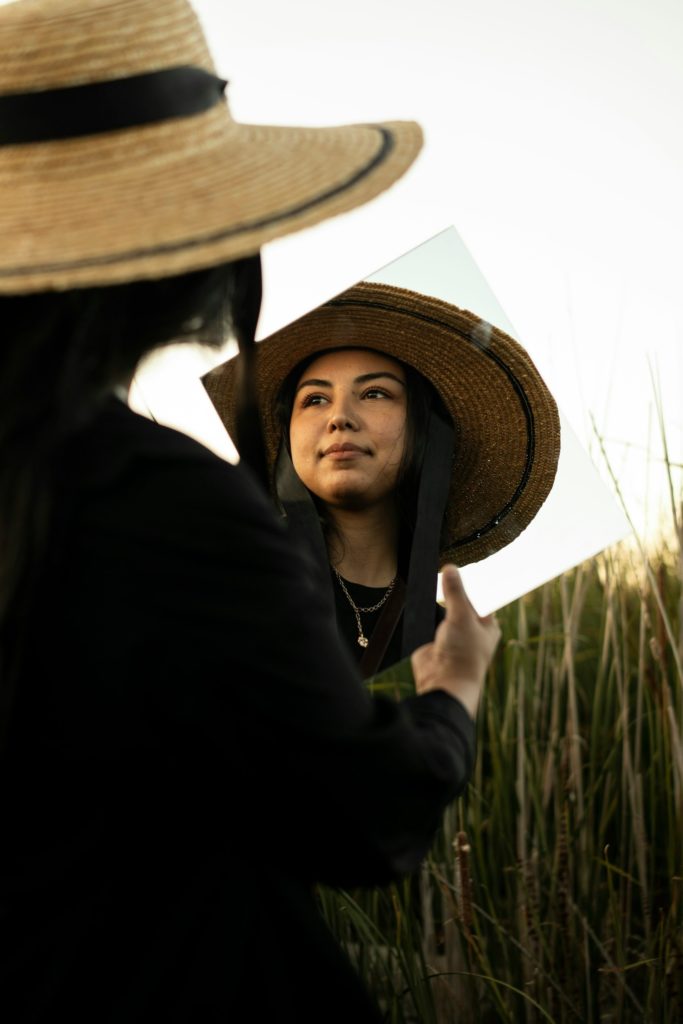 a woman wearing a hat and holding a mirror