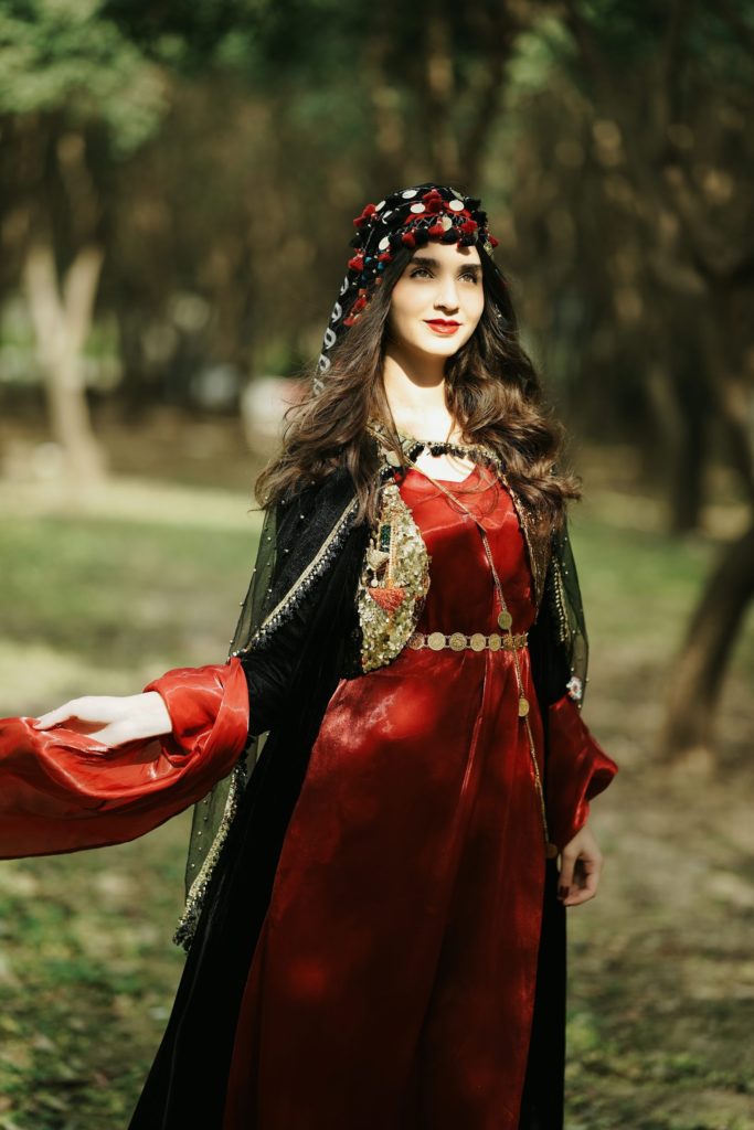uzbekistan woman in a red dress is standing in the woods