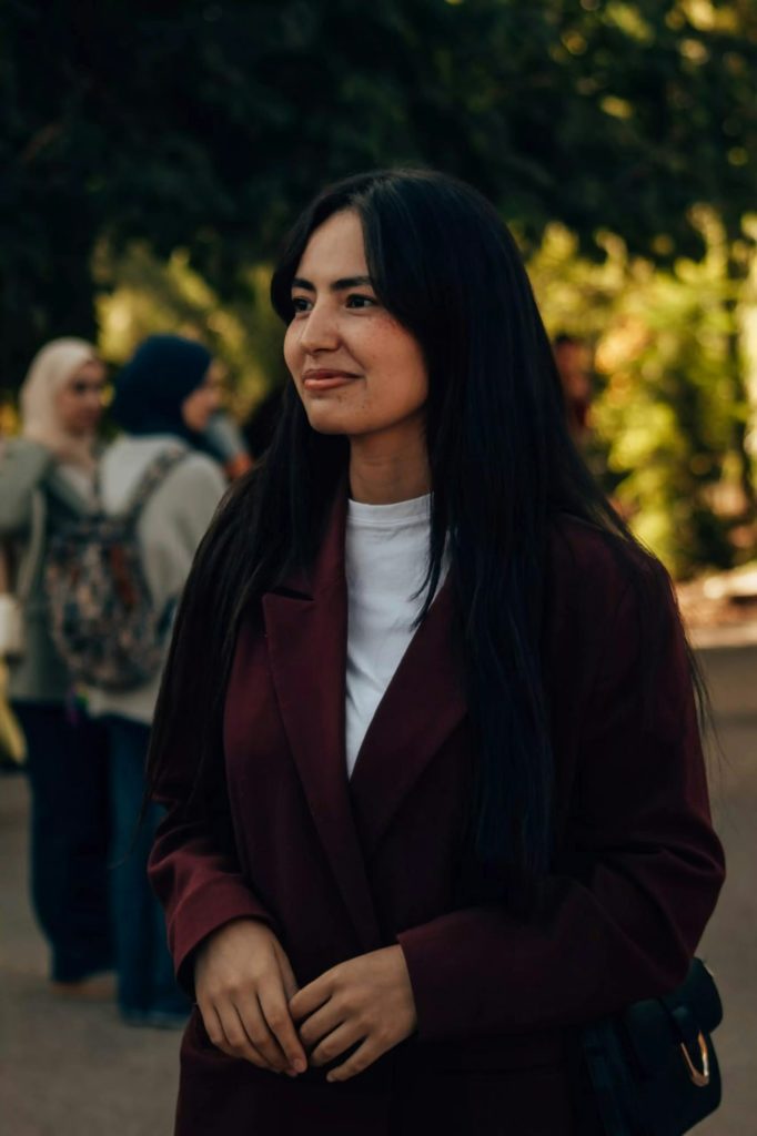 uzbekistan woman smiles outdoors with people in background.