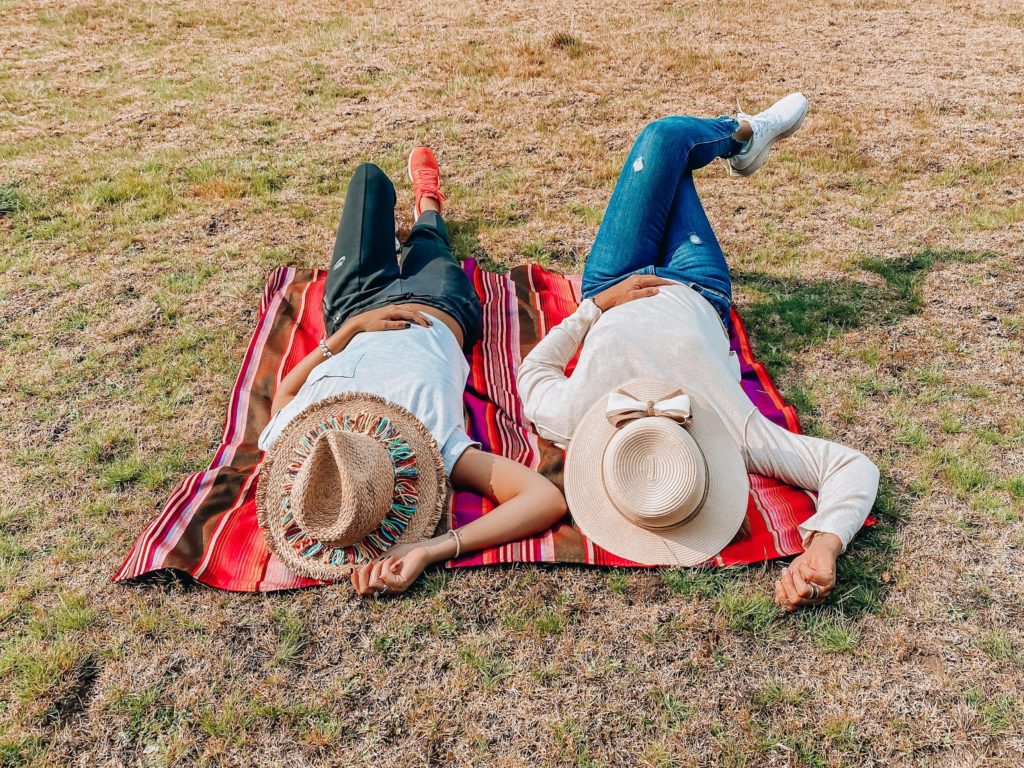 woman in brown sun hat lying on green grass field during daytime