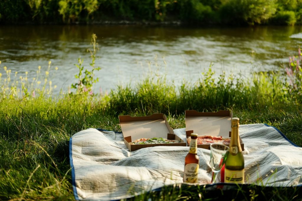 Two bottles of wine and two bottles of wine on a blanket near a river