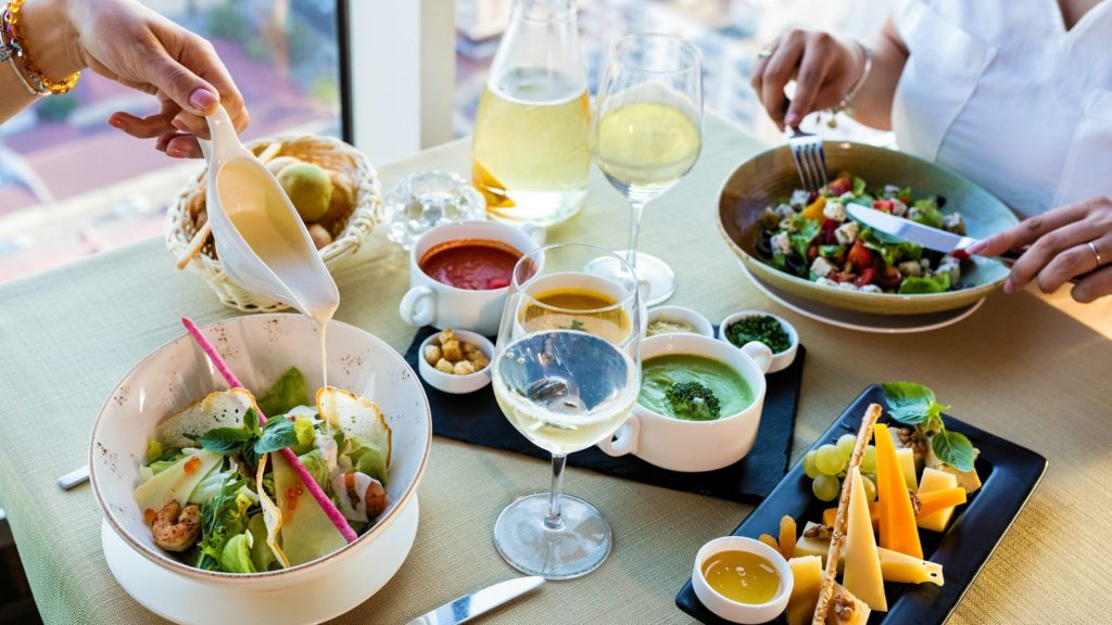 vegetable salad on white ceramic bowl beside clear wine glass