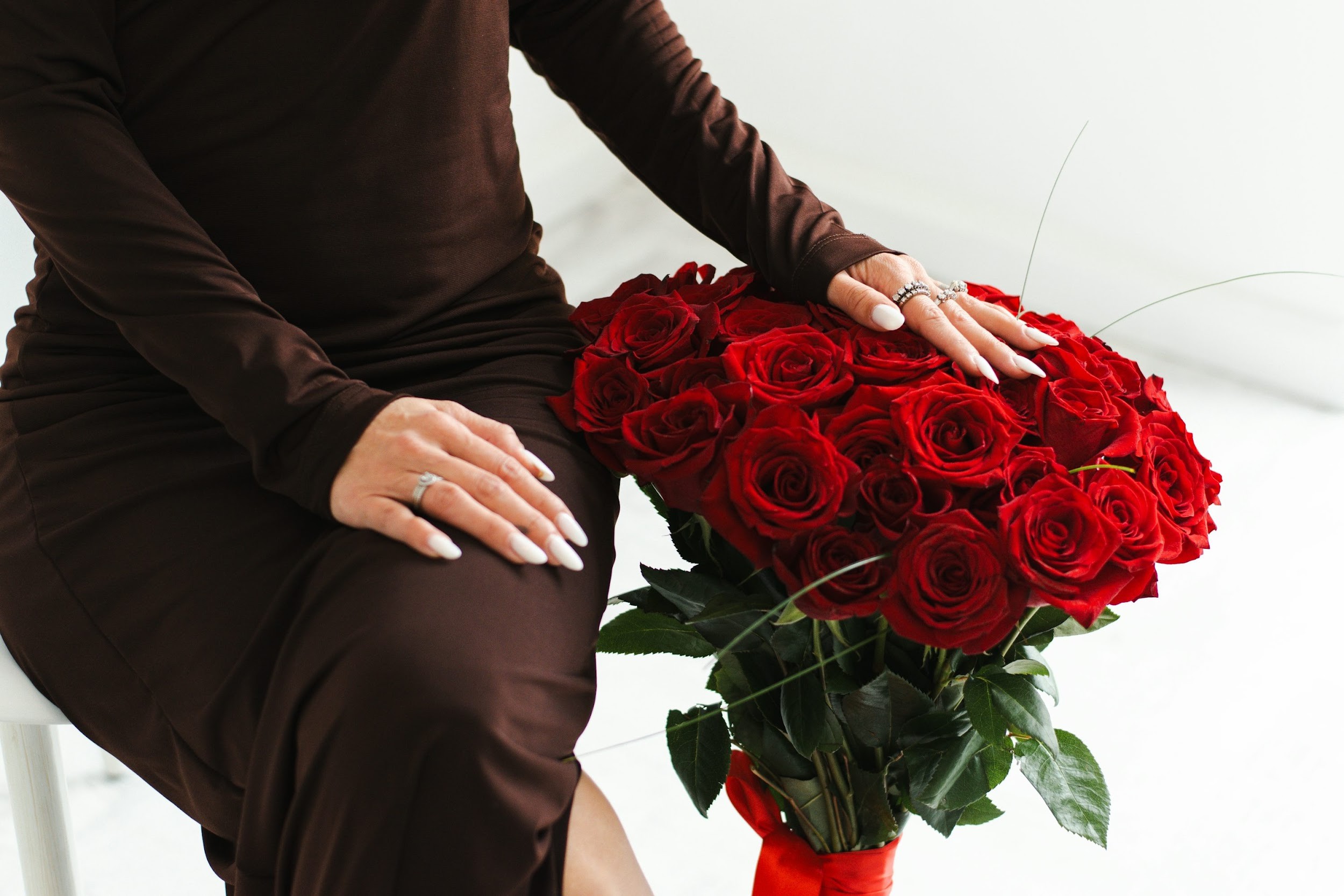 A woman holds a bouquet of red roses.