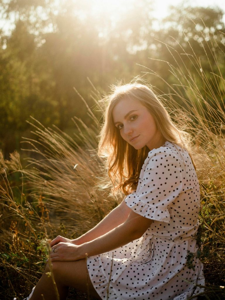 a woman sitting in a field of tall grass