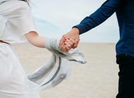man and woman holding hands together in field during daytime