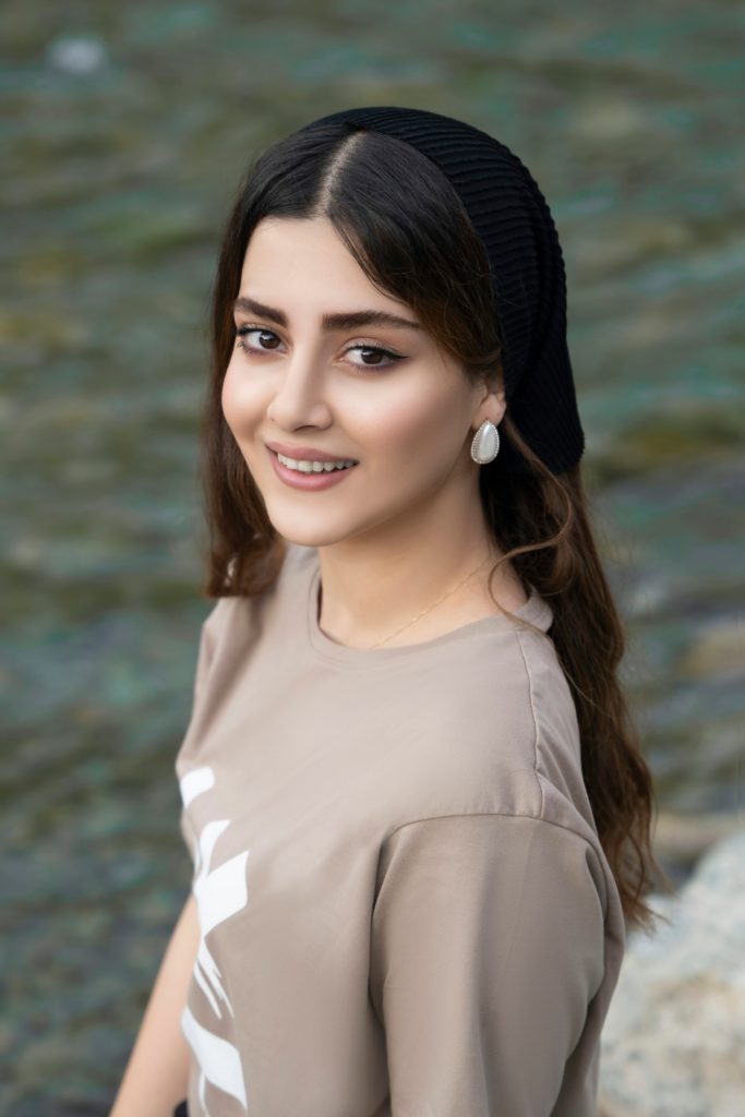 woman in white crew neck shirt and black knit cap smiling