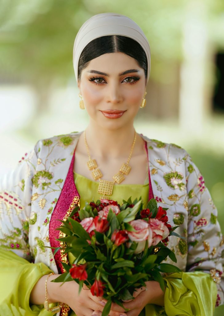 a woman in a green dress holding a bouquet of flowers